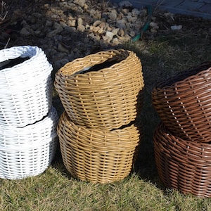 以下が含まれることがあります： 白、茶色、自然色の3つの籐製の植木鉢が、2つずつ積み重ねられています。鉢は、きつく均一なパターンで編まれています。