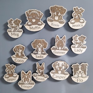 May include: A selection of wooden dog name tags. Each tag showcases a different dog breed, with a name engraved beneath. Names include Meg, Muffin, Roxie, Jessica, Coco, Sadie, Gunner, Lady, Jasper, Raven, Casper, Flo, and Trooper.