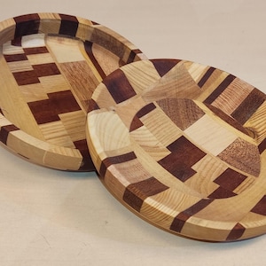 Op de afbeelding: Twee houten kommen met een geometrisch patroon van licht en donker hout. De kommen zijn op elkaar gestapeld.