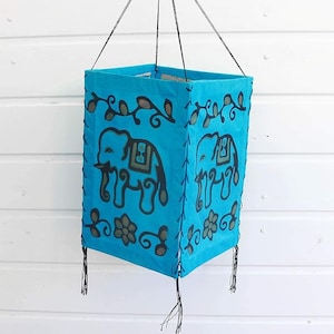 May include: A blue fabric lantern with black elephant designs and black tassels hanging from the bottom.