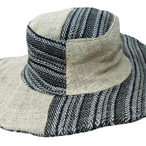 May include: A wide-brimmed hat with a patchwork design. The hat features a natural beige fabric contrasted with sections of black and white patterned fabric. The brim is wide, offering sun protection. The hat is suitable for outdoor wear.