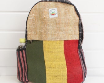 May include: A multi-coloured hemp backpack with a black zipper and a small green leaf logo. The backpack has a striped pocket on the side and is made of a woven fabric.