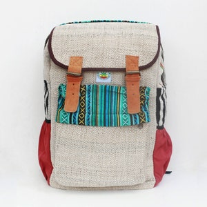 May include: A beige hemp backpack with a large front pocket featuring a colorful woven pattern. The backpack has brown leather straps and red accents.