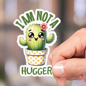 May include: A white sticker with a cartoon cactus in a yellow pot with white polka dots. The cactus has a pink flower and a smiling face. The text "I AM NOT A HUGGER" is written in a white outline around the cactus.