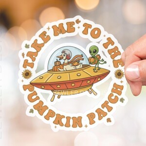 May include: A circular sticker with the text "TAKE ME TO THE PUMPKIN PATCH" in orange. The sticker features a cartoon duck in a spaceship with pumpkins and an alien. The sticker has a retro, fall theme.