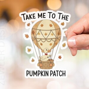 May include: A sticker featuring a cartoon hot air balloon with a duck in a basket, surrounded by autumn leaves. The text reads "TAKE ME TO THE PUMPKIN PATCH". The balloon is tan and brown.