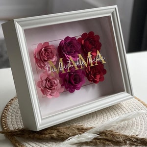 Bilderrahmen mit Papierrosen in Rosa und Rot und einen goldenen Schriftzug mit dem Wort Mama