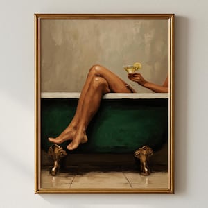 May include: Framed art print of a person relaxing in a dark green clawfoot bathtub, holding a cocktail with a lemon slice. The artwork features a gold frame and a neutral background, creating a serene and elegant aesthetic.