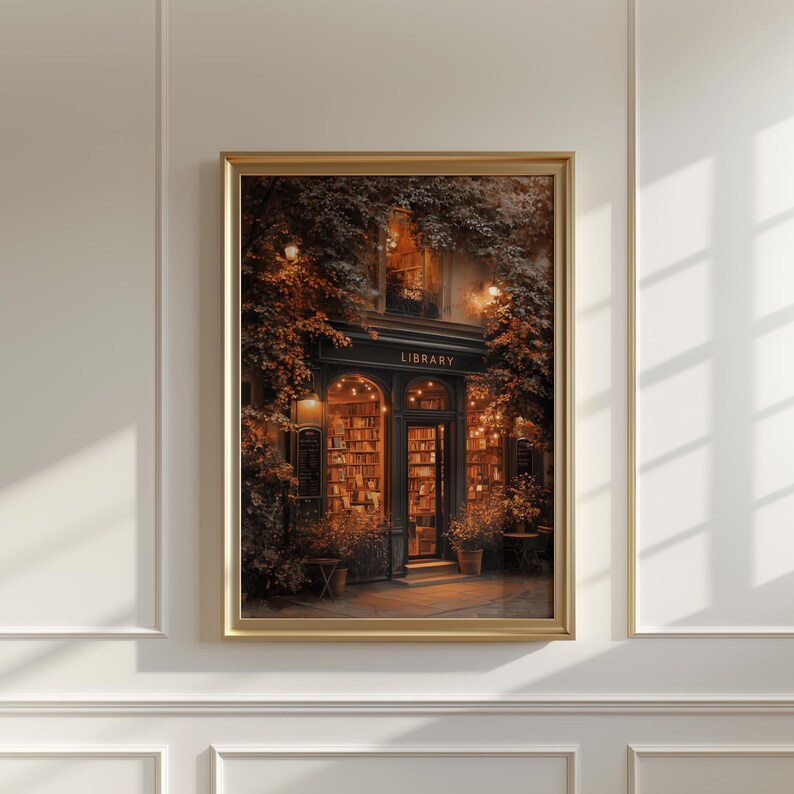 May include: A framed print of a quaint library storefront. The shop is framed by lush foliage and warm lighting. The word "LIBRARY" is displayed above the entrance. Bookshelves are visible through the glass doors and windows.