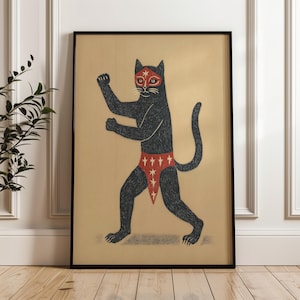 May include: A framed art print featuring a black cat in a wrestling pose. The cat wears a red mask and trunks adorned with white stars. The artwork has a vintage aesthetic, with a tan background and a black frame.