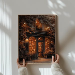 May include: A framed print of a library exterior. The image shows a dark, ornate entrance with the word "LIBRARY" above the door. The entrance is surrounded by lush greenery and warm lighting, with bookshelves visible inside.