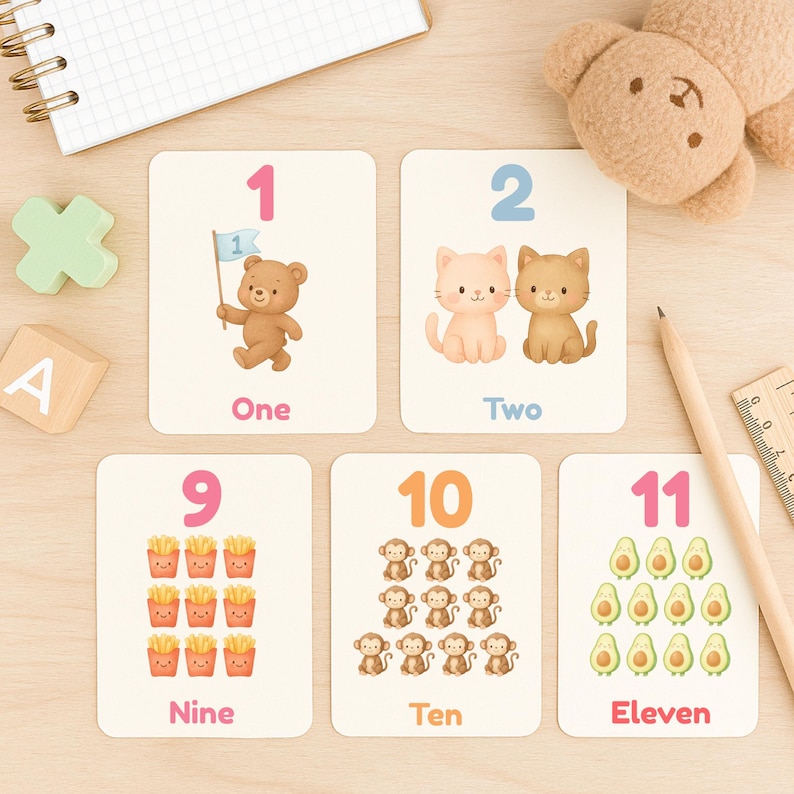 May include: Educational flashcards featuring numbers 1, 2, 9, 10, and 11. Each card displays a number with corresponding illustrations of a bear, cats, french fries, monkeys, and avocados. The word for each number is also printed.