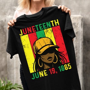 May include: Black t-shirt featuring a vintage-style graphic of a woman wearing a yellow baseball cap. The graphic includes the words "Juneteenth" and "June 19, 1865" in red, yellow, green, and black.