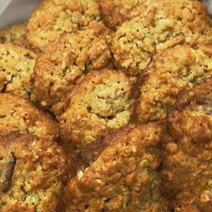 May include: A close-up of a plate of freshly baked oatmeal cookies. The cookies are golden brown and have a slightly crispy texture. They are arranged in a random pattern on the plate.