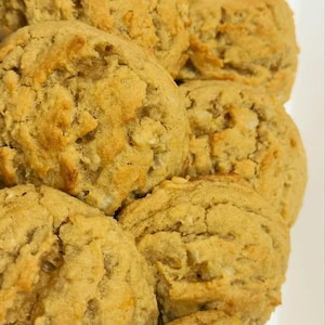 May include: A close-up shot of several golden-brown cookies. The cookies have a slightly rough texture and appear to be freshly baked. They are arranged closely together, suggesting a batch of homemade treats.