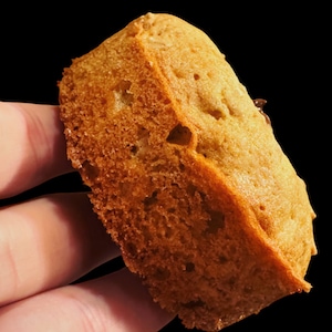 Könnte beinhalten: Nahaufnahme eines goldbraunen Brotlaibs mit leicht knuspriger Kruste. Das Brot wird in einer Hand gehalten, und die Textur des Brotes ist sichtbar.