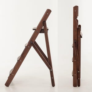 May include: A dark brown wooden folding step stool with three steps and a small top platform. The stool is shown open and folded, revealing its compact design. The steps are a light gray color.