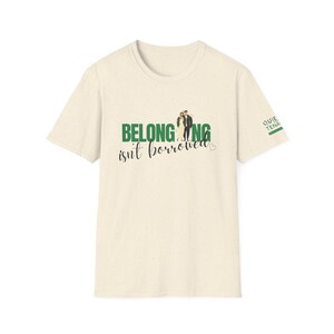May include: Cream-colored t-shirt with the text "BELONGING isn't borrowed" in green, featuring a couple graphic. The sleeve has the text "QUIET TENA" in green. A simple, everyday tee.