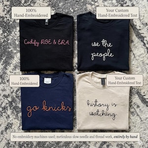 May include: Four t-shirts with hand-embroidered text. The shirts are black, navy blue, and beige. The text includes "Codify ROE & ERA", "we the people", "go knicks", and "history is watching".