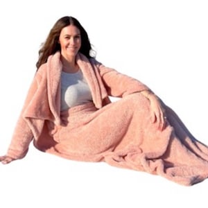 Pu&ograve; includere: Una morbida e soffice coperta rosa con collo a scialle. La coperta &egrave; realizzata in un materiale soffice e confortevole, perfetta per coccolarsi sul divano.