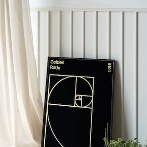 May include: A black framed poster with a gold graphic of the golden ratio, a mathematical concept that appears in nature. The poster has the text "Golden Ratio" and "1.618" in gold lettering.
