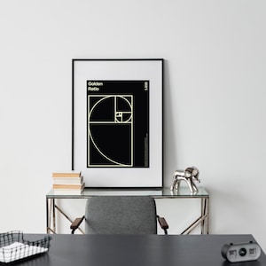 May include: A black and white poster with the text "Golden Ratio" and a geometric design of a spiral. The poster is framed in a black frame and is hanging on a white wall.