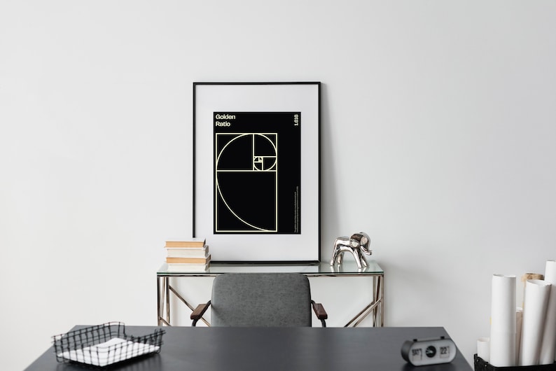 May include: A black and white poster with the text "Golden Ratio" and a geometric design of a spiral. The poster is framed in a black frame and is hanging on a white wall.