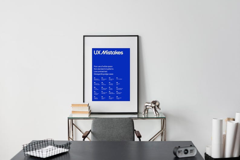 Op de afbeelding: Een ingelijste poster met een blauwe achtergrond en witte tekst die "UX Mistakes" luidt. De poster somt veelvoorkomende UX-fouten op, zoals slecht gebruik van witruimte, niet-standaard UI-patronen, tekst met laag contrast en het negeren van randgevallen. De poster hangt aan een witte muur boven een bureau met een zwart oppervlak, een zilveren olifantenbeeldje en een stapel boeken.