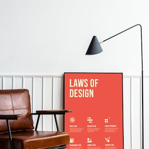 May include: A framed poster with a red background and the text "LAWS OF DESIGN" in white. The poster features six different laws of design, each with a corresponding icon and description.