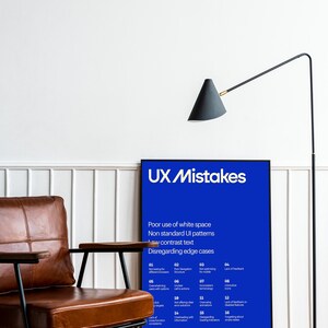 Op de afbeelding: Een poster met een blauwe achtergrond en witte tekst die "UX Mistakes" luidt. De poster somt veelvoorkomende UX-fouten op met nummers en korte beschrijvingen. De poster hangt aan een witte muur met een bruine leren fauteuil en een zwarte staande lamp op de voorgrond.