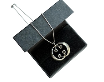 May include: A silver necklace with a circular pendant featuring a black onyx stone and a silver design. The necklace is in a black velvet box.