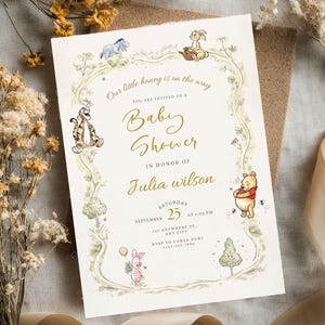 May include: A baby shower invitation featuring Winnie the Pooh characters. The invitation has a cream background with a floral border and the text "Our little honey is on the way". The invitation is for Julia Wilson, with the date September 25.