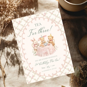 Könnte beinhalten: Eine Einladung zur Teeparty mit dem Text "Tea For three!" und "3rd birthday Par tea!". Sie zeigt Illustrationen eines Hasen, eines Bären und anderer Teeparty-Elemente. Die Einladung ist mit einem Blumenmuster und einem rosa Rand verziert.