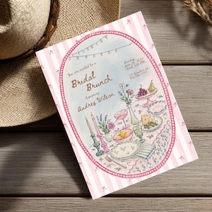 May include: A rectangular invitation card with a pink and white striped border featuring small bow icons. The center oval illustration depicts a table set for a Bridal Brunch honoring Audrey Wilson, with candles, flowers, fruit, and dinnerware.