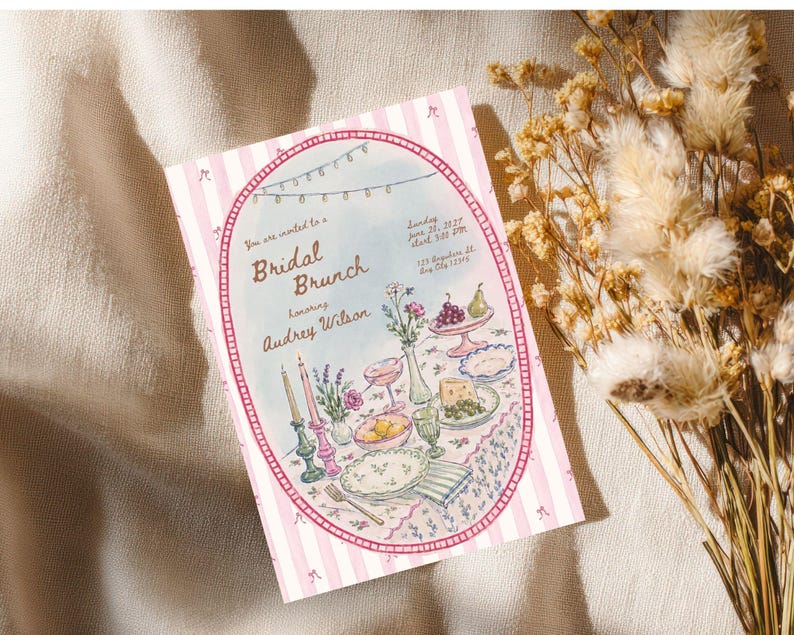 May include: A rectangular invitation card with a pink and white striped border featuring a central oval illustration of a table set for a bridal brunch. The text reads: You are invited to a Bridal Brunch honoring Audrey Wilson, Sunday June 28, 2027, start 3:00 PM, 123 Anywhere St., Any City 12345.