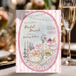 May include: A rectangular invitation card with a pink and white striped border featuring an oval frame. The text reads: You are invited to a Bridal Brunch honoring Audrey Wilson, Sunday June 20, 2027, 3:00 PM, 123 Anywhere St. Any City 12345.