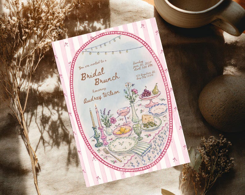 May include: A rectangular invitation card with a pink and white striped border featuring a central oval illustration of a table set for a bridal brunch. The text reads: You are invited to a Bridal Brunch Honoring Audrey Wilson Sunday June 20, 2027 start 3:00 PM 123 Anywhere St. Any City 12345.