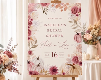Puede incluir: Un letrero rectangular sobre un caballete de madera con el texto WELCOME TO ISABELLA'S BRIDAL SHOWER Fall in Love SAT 16 OCT. El diseño está decorado con ilustraciones de rosas rosas, hojas de palma secas y calabazas blancas otoñales.
