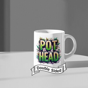 Pode incluir: Caneca de cerâmica branca com as palavras "POT HEAD" em verde e amarelo, rodeada por folhas verdes de cannabis. A caneca tem uma alça curva e o texto "Double Sided" em uma faixa.