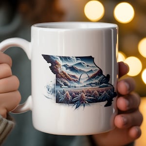 Può includere: Tazza in ceramica bianca con un'illustrazione dettagliata dello stato del Missouri. Il design include un paesaggio con montagne, il Gateway Arch e un campo di piante. La tazza ha un manico standard e una finitura lucida.
