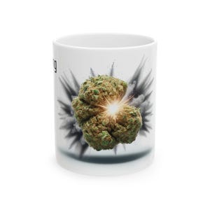 May include: White ceramic mug featuring a green and brown cannabis bud with a bright yellow center, set against a gray and black burst design. The word "ing" is partially visible on the left side of the mug.