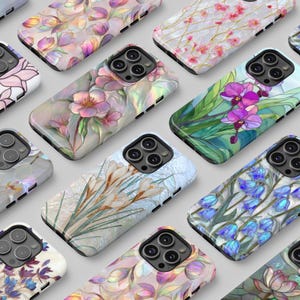 May include: A collection of floral-themed phone cases. The cases feature various designs, including pink and purple flowers, orchids, and bluebells. The cases have a glossy finish and are arranged on a light gray surface.