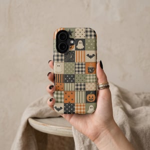 May include: A rectangular phone case featuring a patchwork grid design with various Halloween-themed patterns including ghosts, pumpkins, bats, stars, plaid, and stripes in a color palette of muted orange, sage green, cream, and black.