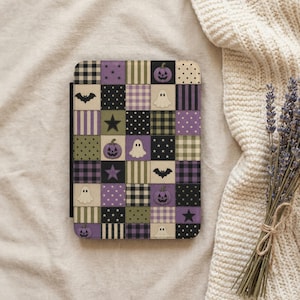 May include: A rectangular tablet case featuring a patchwork design of squares in purple, olive green, black, and cream. The pattern includes motifs of ghosts, jack-o'-lanterns, bats, stars, polka dots, buffalo plaid, and vertical stripes.