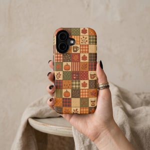 May include: A phone case featuring a patchwork grid design with autumn-themed illustrations including orange pumpkins, brown coffee mugs, and various fall leaves in shades of red, orange, green, and yellow against plaid and polka dot patterns.