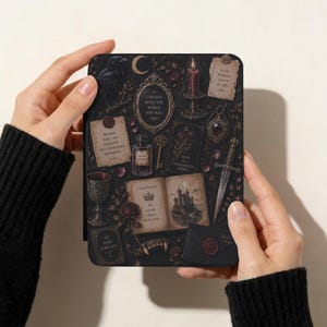 May include: A black e-reader cover featuring a dark, intricate pattern of a raven, a burning candle, a dagger, a goblet, an ink bottle, and an open book. The design includes text snippets like I WOULD BURN THE WORLD FOR YOU and BEWARE FOR I AM FEARLESS.