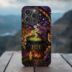 May include: A smartphone case featuring a stained glass style illustration of a black cauldron with a triple moon symbol, emitting green smoke. A witch hat, a lit candle, stacked books, and a purple potion bottle are arranged below the cauldron.
