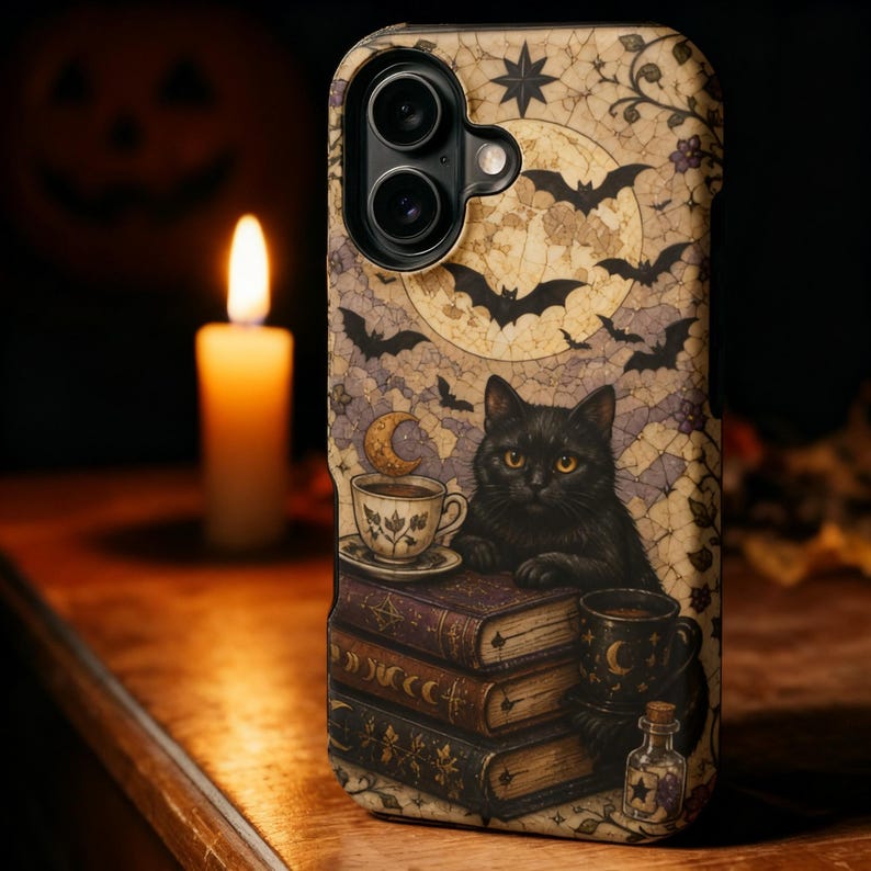 May include: A smartphone case featuring a graphic illustration of a black cat resting on a stack of three vintage books. The design includes a full moon, flying bats, a teacup, a mug, and a small glass bottle, all set against a beige background.