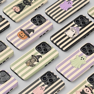 May include: A collection of smartphone cases featuring various Halloween-themed illustrations including pumpkins with witch hats, ghosts in shades of purple and green, and a raccoon with a broom, all set against striped backgrounds in pastel colors.