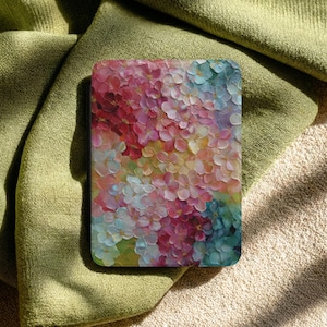 May include: A rectangular decorative item with a floral design. The artwork features a close-up of colorful flowers in shades of pink, red, blue, and yellow. The item is resting on a green and beige fabric.